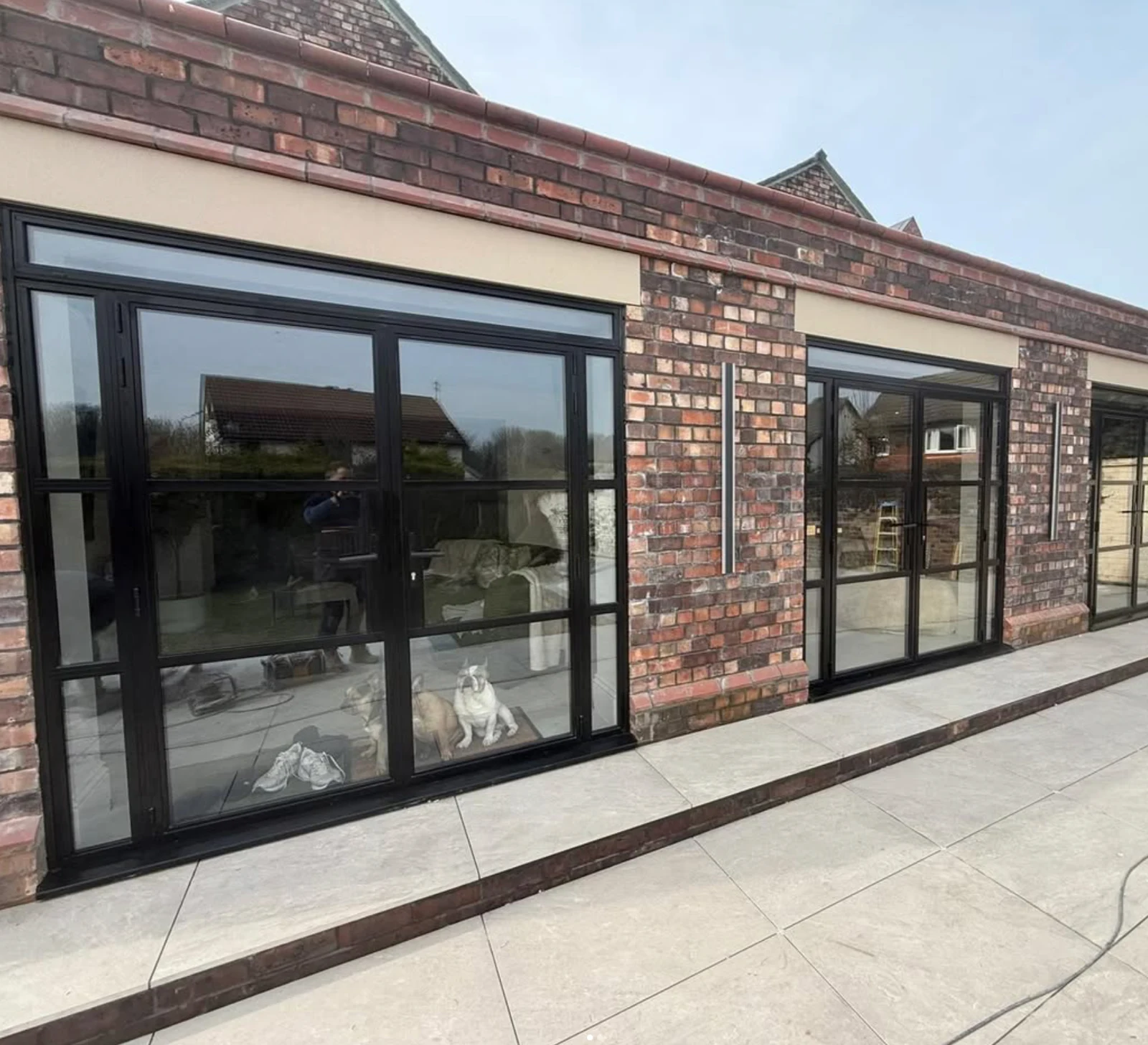 Black bifold doors across the rear of a brick home